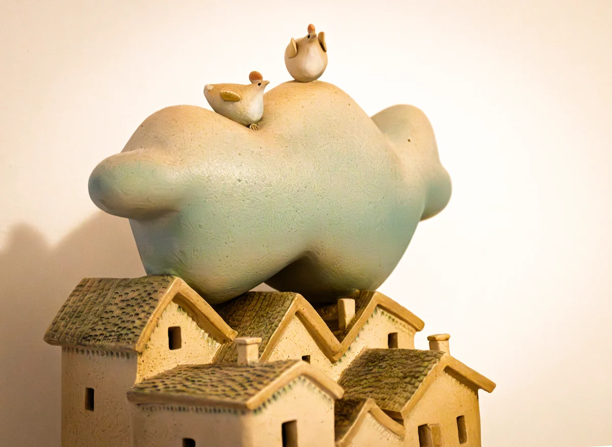 Ceramic cloud and birds sculpture above village rooftops — The Wild Nest, Ferrara