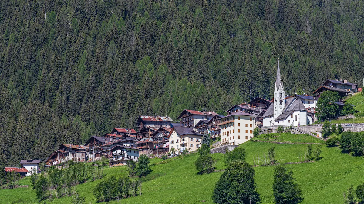 Dolomites alpine village with church and forest